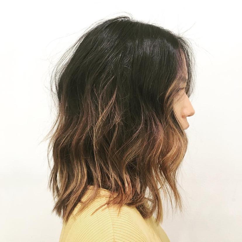 Medium-length wavy hair with black roots transitioning to brown and blonde ombre