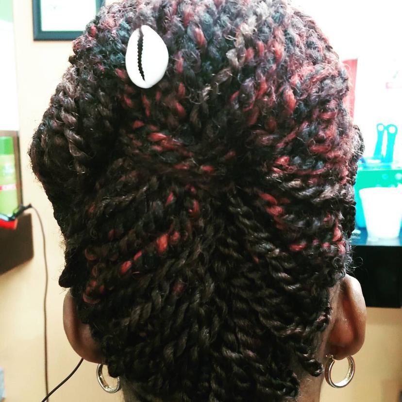 A medium-length twist out updo hairstyle with a cowrie shell accent. by Beautiful Image Hair Studio