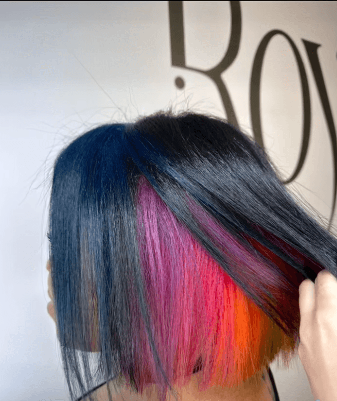 Rainbow under-dye bob with black roots transitioning into blue, pink, and orange highlights in Manhattan, New York