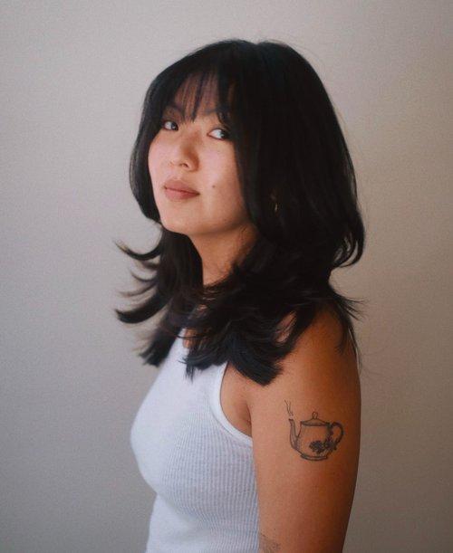 Medium-length layered bob with shaggy texture and curtain bangs.