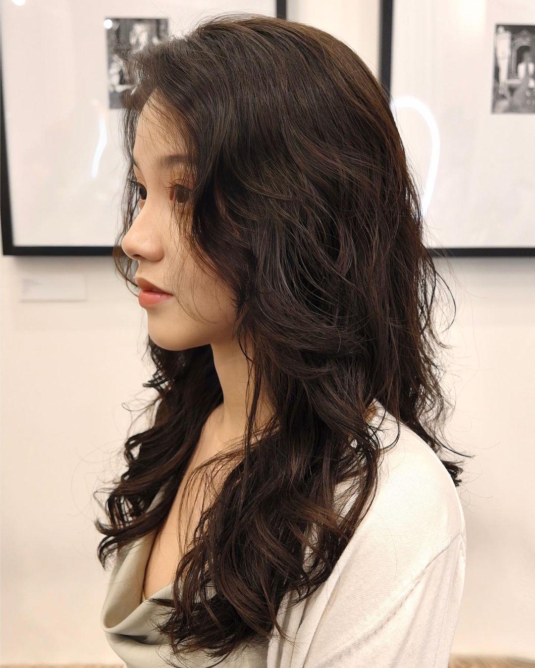 Long, dark brown hair cascades in soft, wavy layers with voluminous locks and side-swept bangs. 👩🏻‍🦱Hair by @hiro.nonstop 👩🏻‍🦱 2