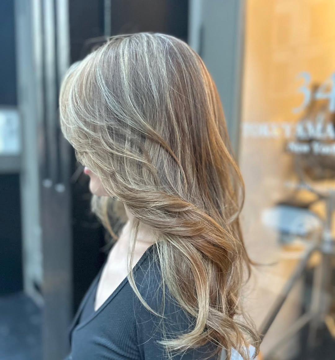Beautifully styled long, wavy hair with light brown and golden blonde highlights, featuring soft curls and natural volume for an elegant look. 2