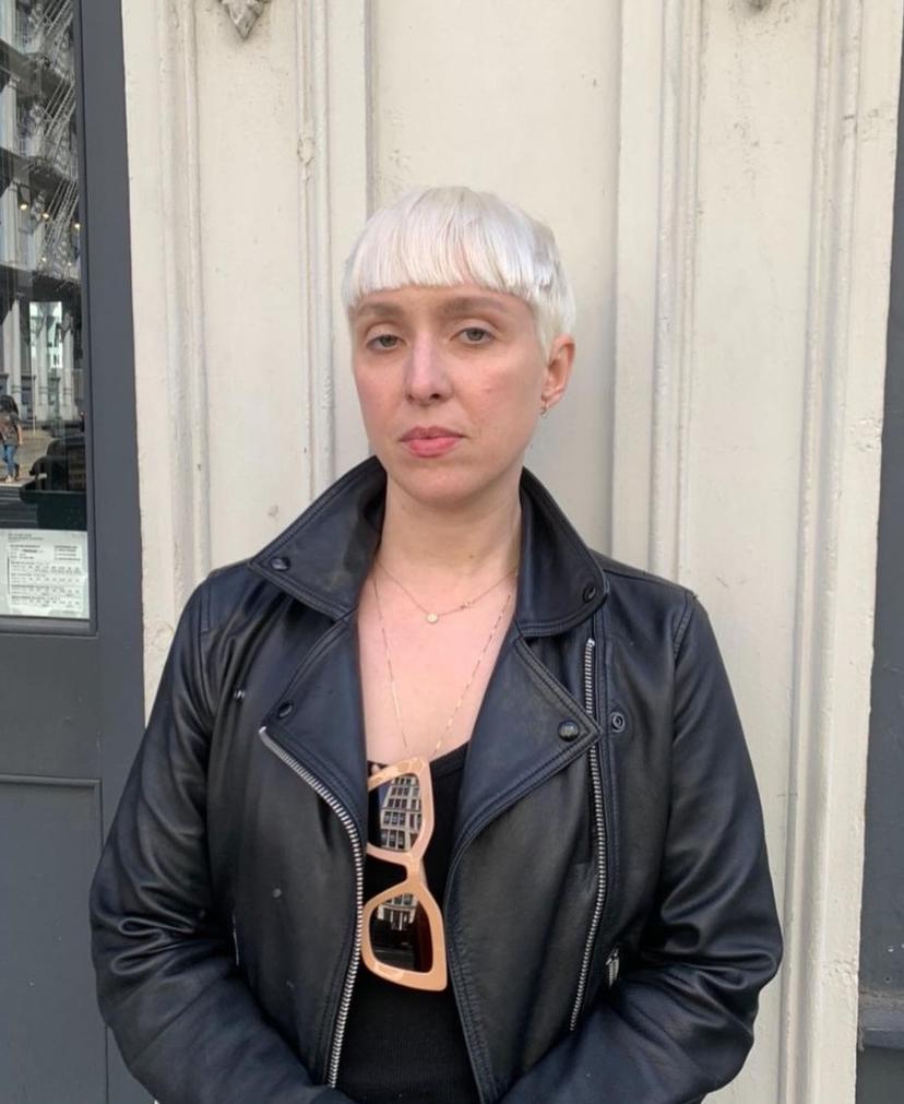 Short, straight platinum blonde pixie cut with distinguishing micro bangs.