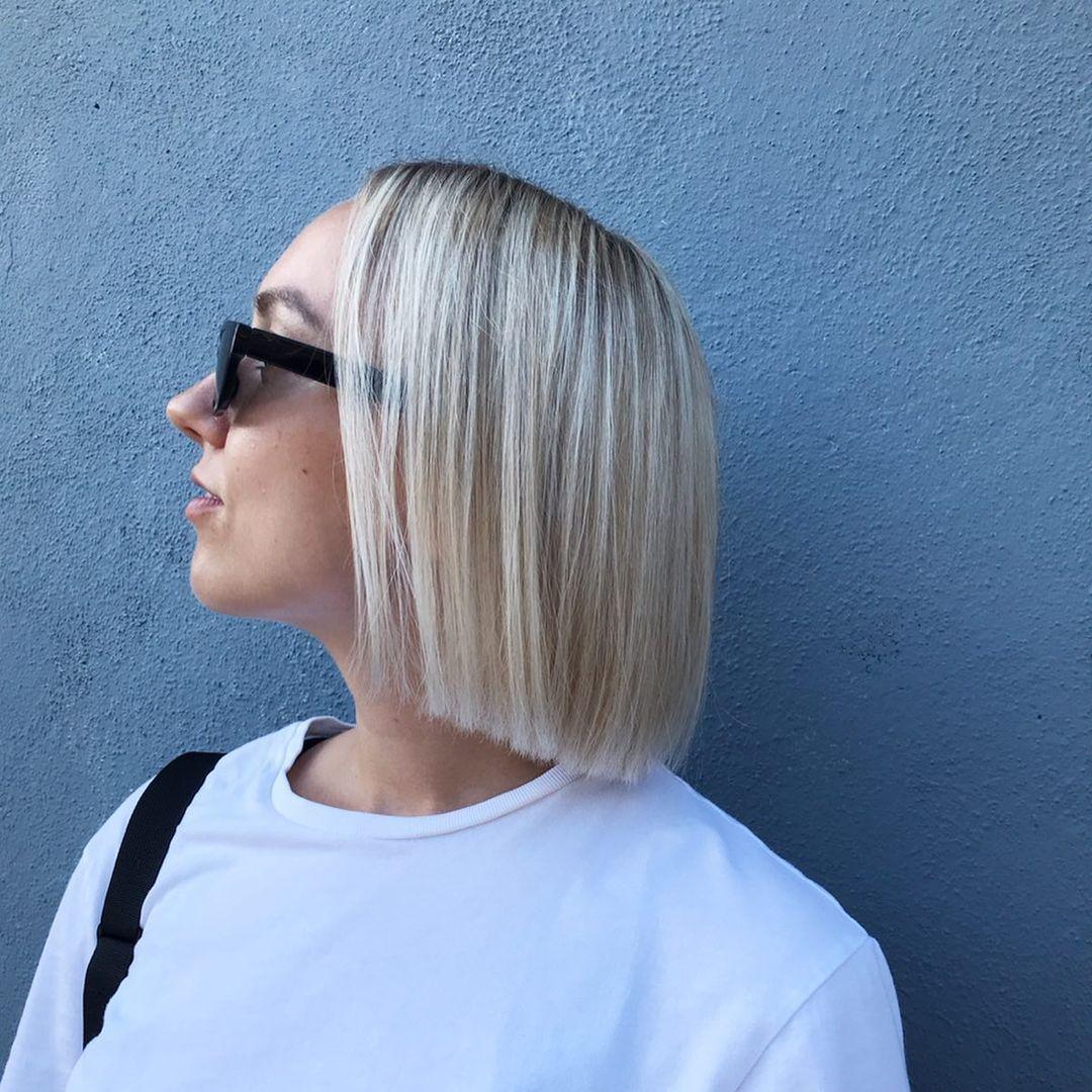 Medium-length platinum blonde straight hair in a classic blunt bob with a glossy finish and a subtle side part. 1