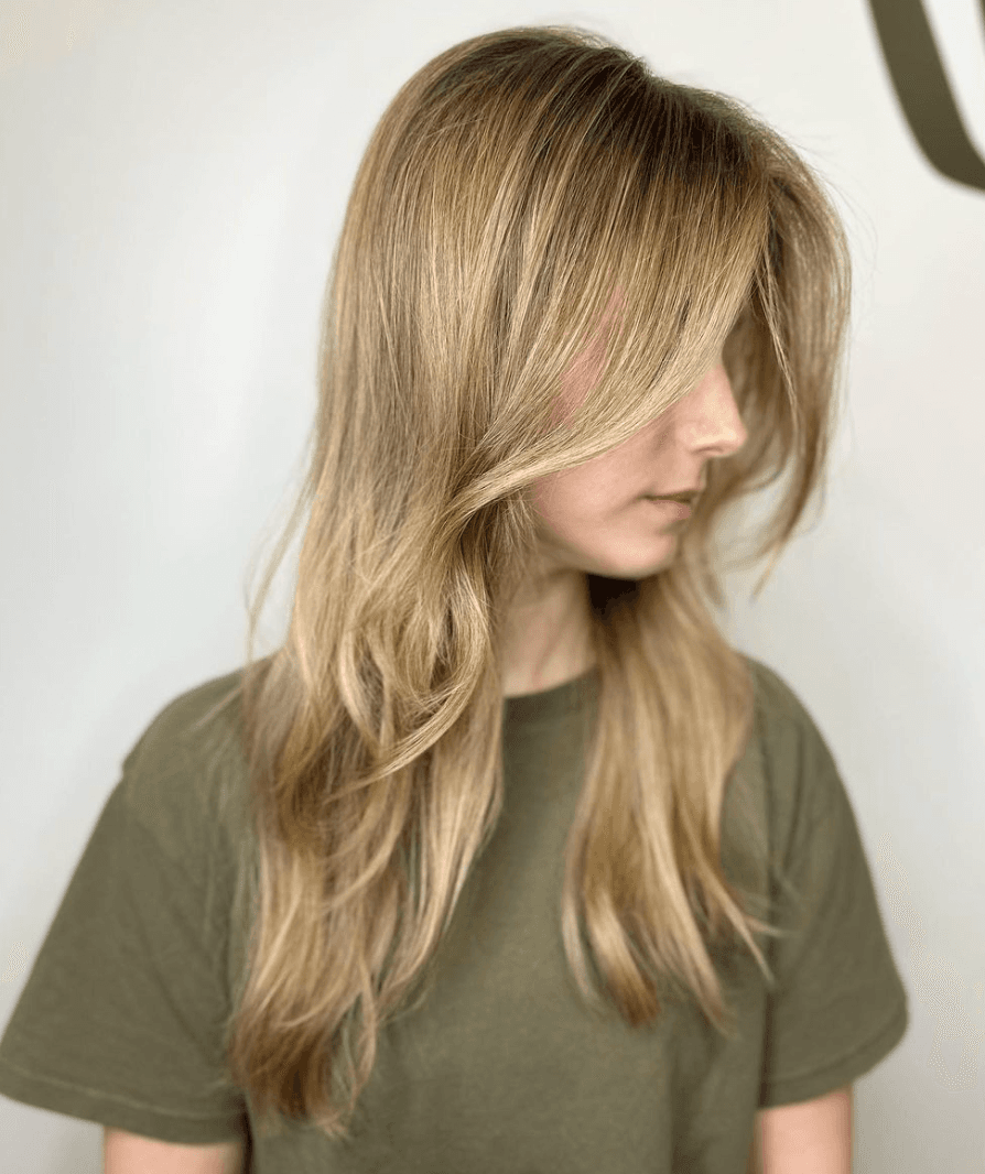 Long wavy blonde hair with side-swept bangs and face-framing layers, featuring a layered cut for added volume and texture.

Color by @simabeautynyc
 1
