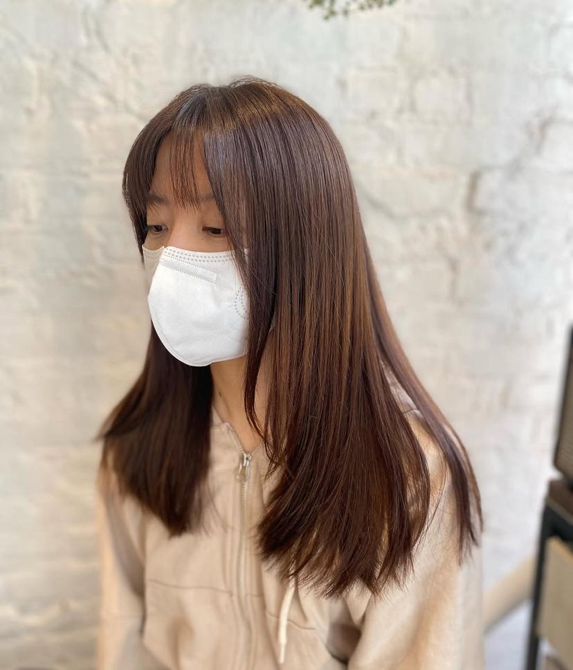 Long layered haircut with face-framing curtain bangs for a trendy look.