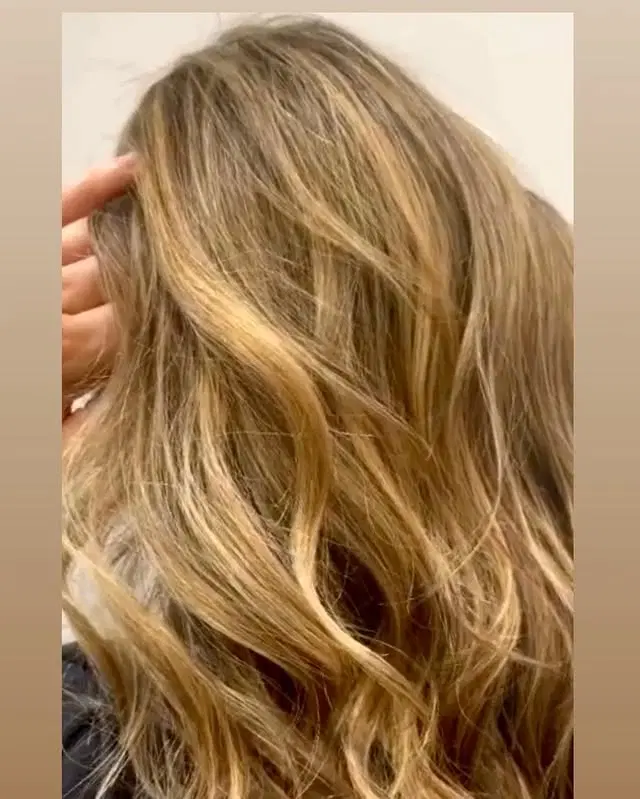Long, wavy hairstyle with a blonde balayage and golden blonde highlights.