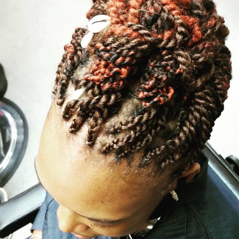 A short twist out hairstyle with brown and copper tones, accented with shell accessories, embodying a boho-chic vibe.