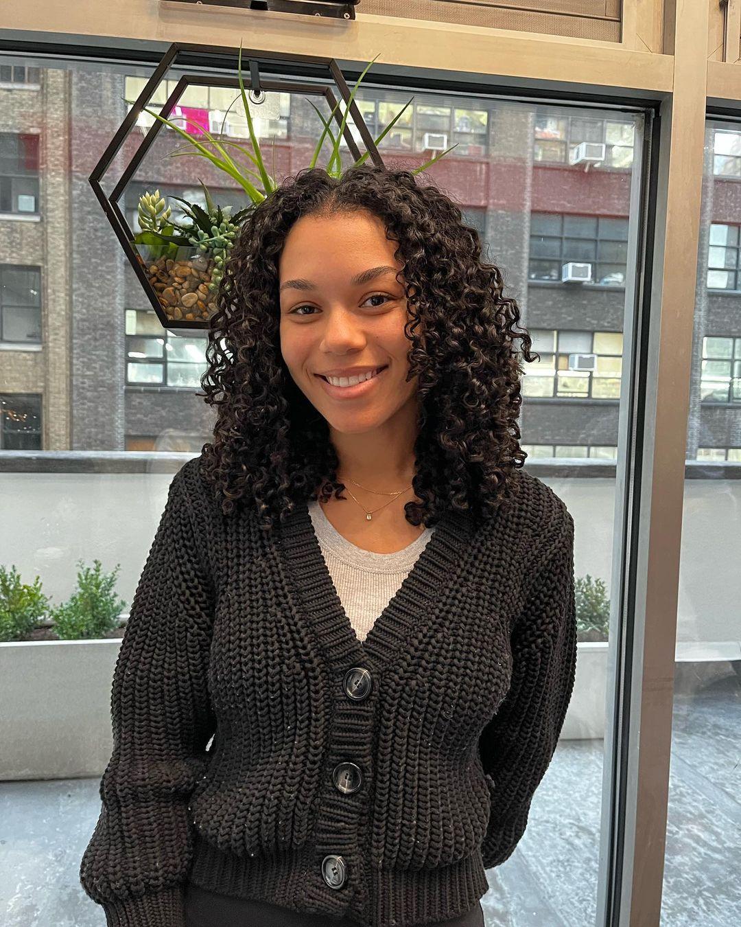 Naturally curly, medium-length black hair with defined and voluminous curls reaching shoulder length, exhibiting healthy shine. 1