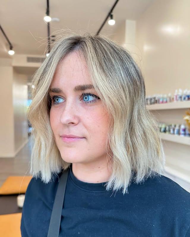 Icy blonde wavy lob with shadow roots, creating a soft transition