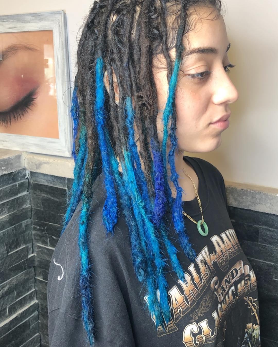 Long, coiled dreadlocks with vibrant blue and bright blue tipped ends, creating an edgy and unique two-tone look. 1