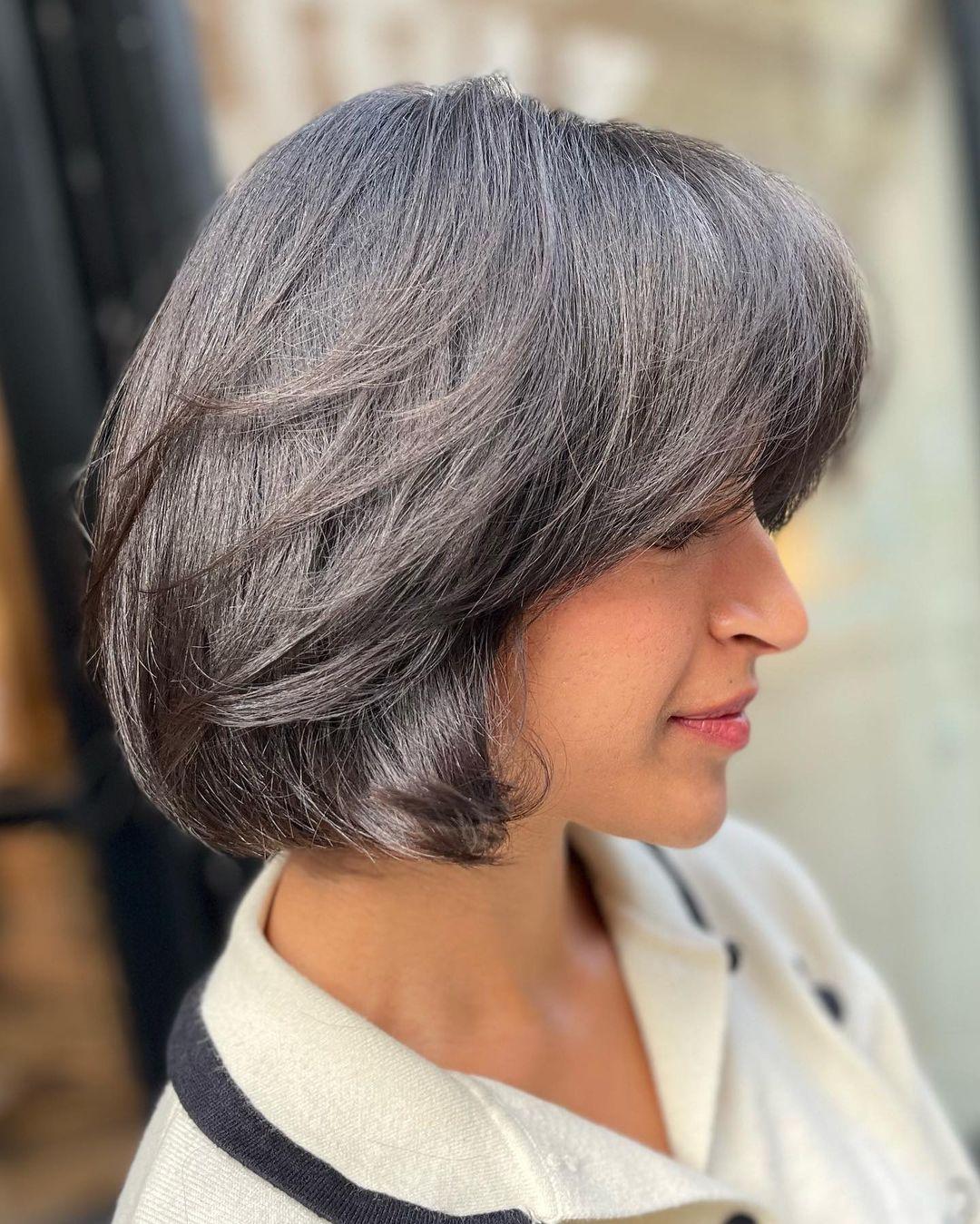 A stylish and modern short bob with a sophisticated blend of silver and grey. The straight hair features a side-swept fringe and layered sections for added movement and depth. 1