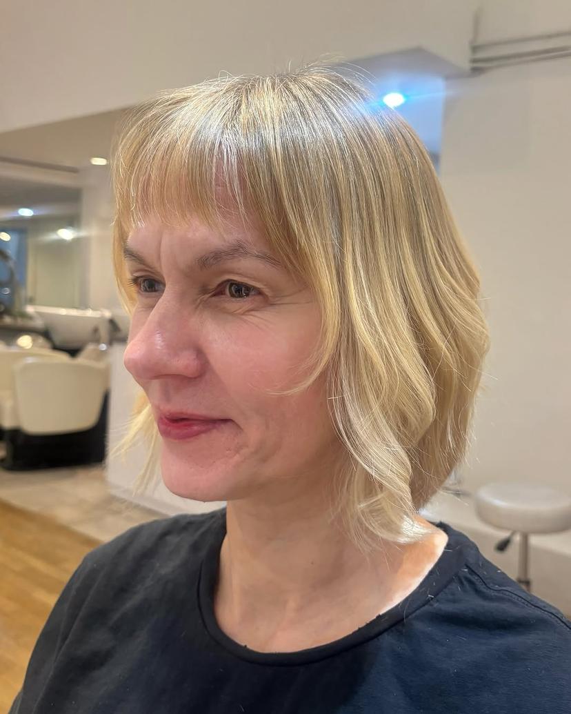 Shoulder-length bob with face-framing curtain bangs and soft waves.