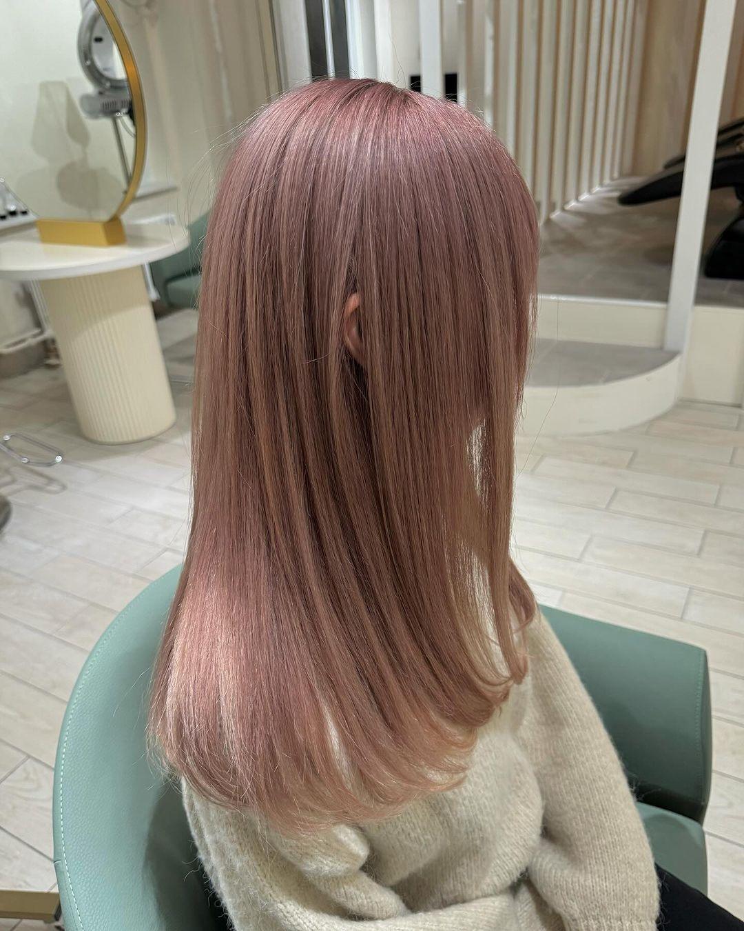 Smooth, straight medium-length hair in a sleek and glossy rose gold shade, featuring a soft pink hue. The hairstyle includes a side-part which allows the hair to drape naturally over the shoulders. 3