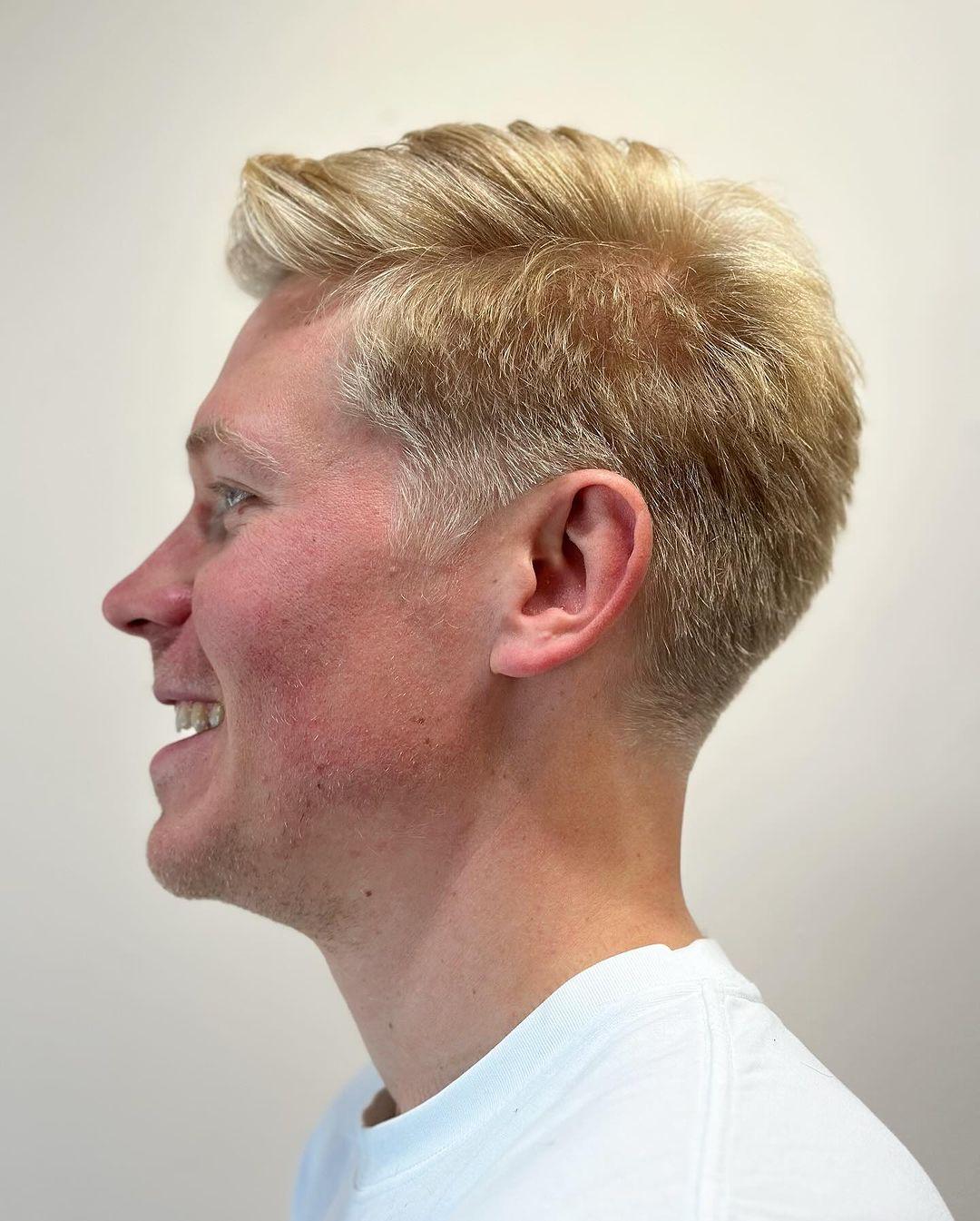 A sleek and short blonde hairstyle with tapered sides and a textured top, featuring a subtle side part. 1