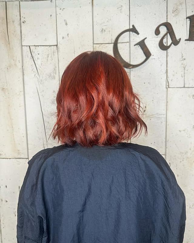 A wavy bob with a blunt cut and vibrant copper and red tones.