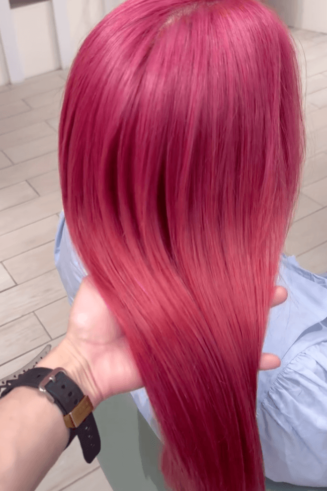 Long, straight hair with a vibrant pink-reddish gradient.