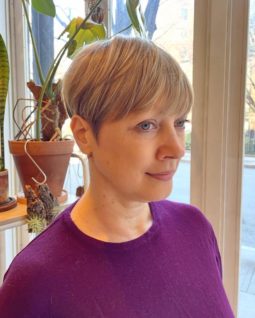 A short pixie cut with textured bangs, featuring blonde hair for a modern classic look.