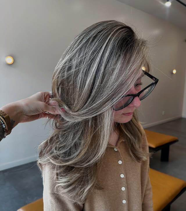 Ash blonde money piece balayage on a layered medium length haircut