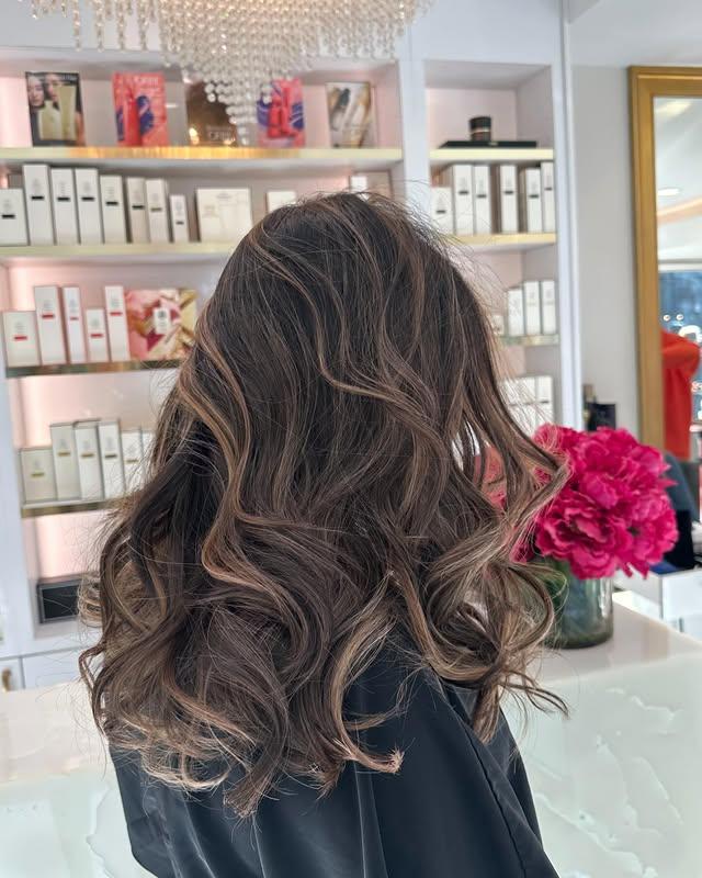 A wavy, medium-length hairstyle with a balayage color technique creating natural-looking beach waves.
