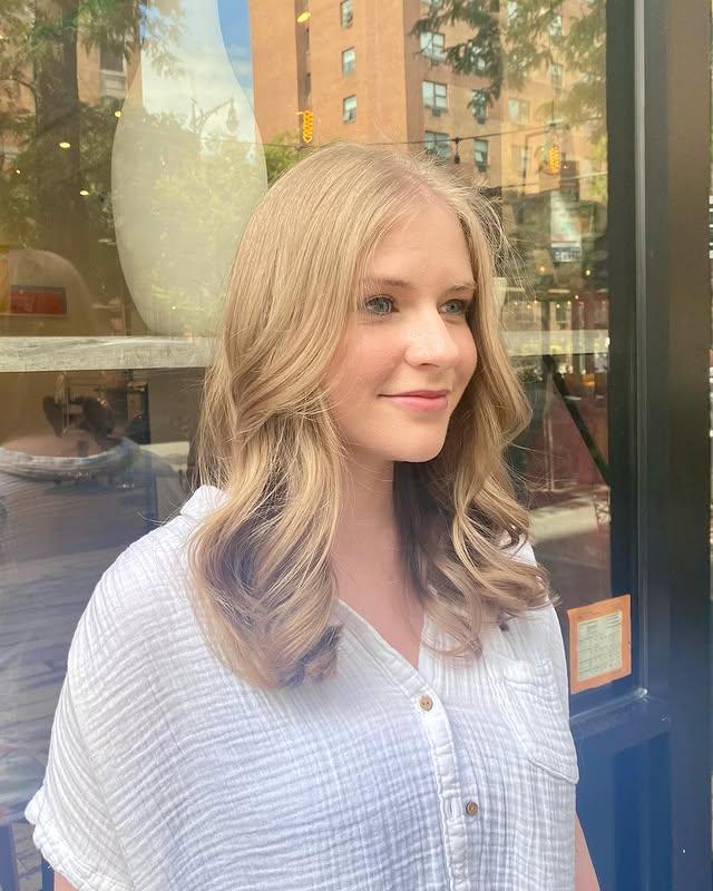 A medium-length wavy hairstyle with a blonde balayage and beachy waves.