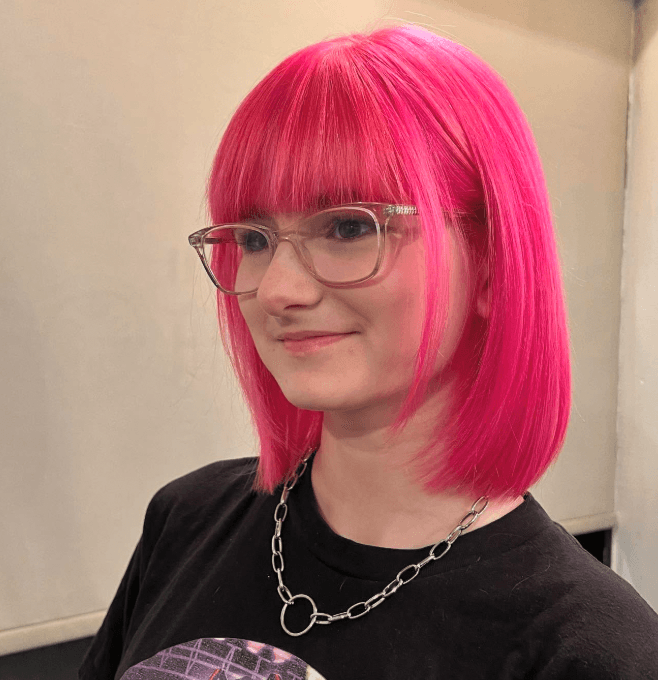 Blunt bob haircut with straight bangs and a vibrant pink color.