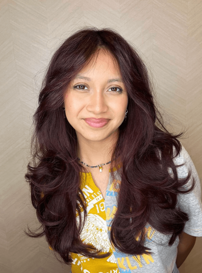 Long, wavy, layered hairstyle in rich burgundy color, with a side part and face-framing layers.

Cut and style by @juliamannino_hair
 3