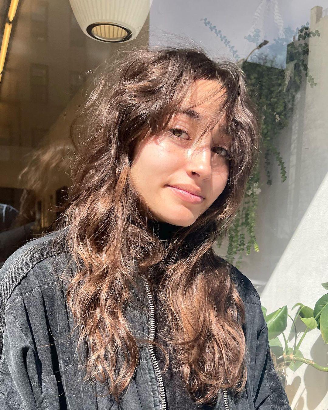 Long, wavy brown hair with natural highlights, featuring messy waves, soft layers, and face-framing tendrils. 1