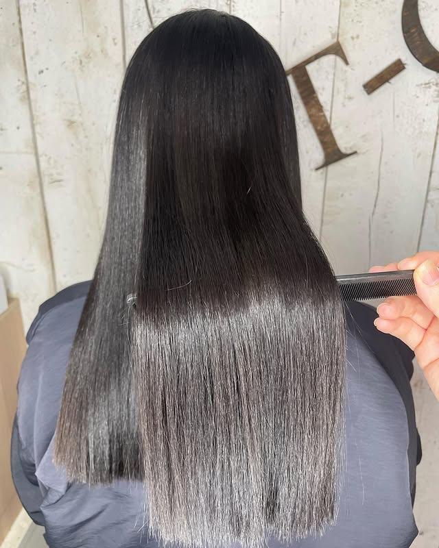 A modern, sleek and shiny straight hairstyle with a blunt cut, embodying the glass hair trend.