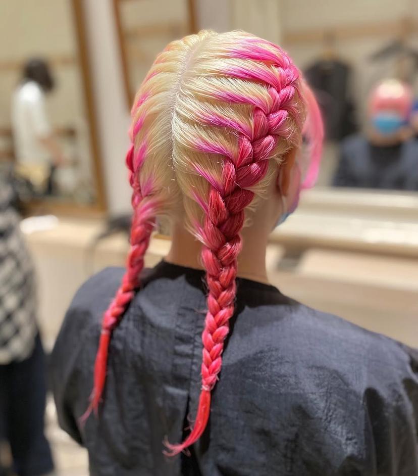 Two braided pigtails featuring vibrant pink streaks, creating a bold and trendy two-tone look.