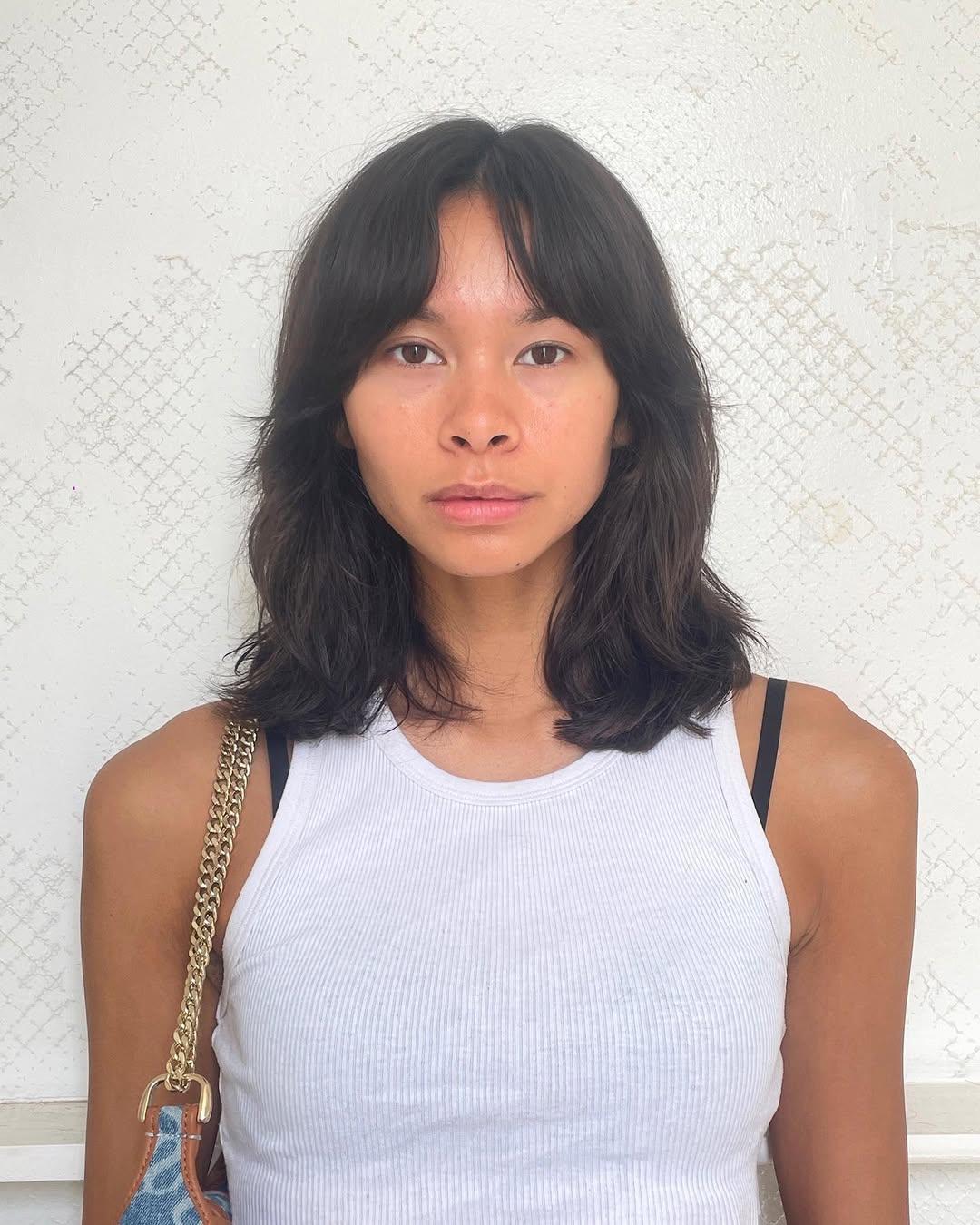 A casual medium-length cut with natural waves, soft layers, and curtain bangs, creating a modern and laid-back style. 1