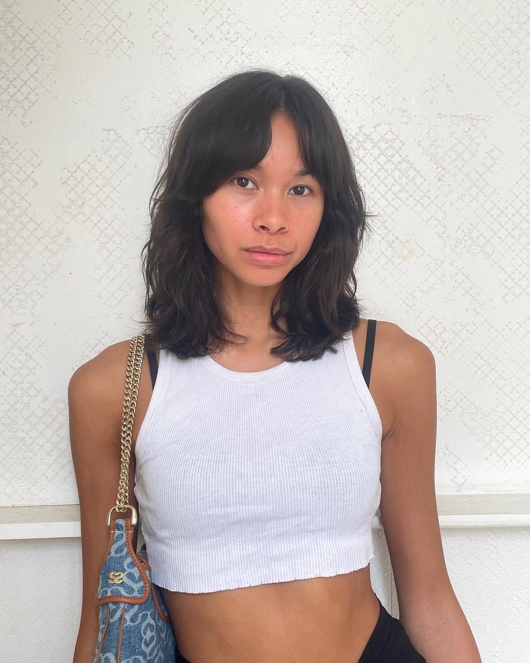 A casual medium-length cut with natural waves, soft layers, and curtain bangs, creating a modern and laid-back style. 2
