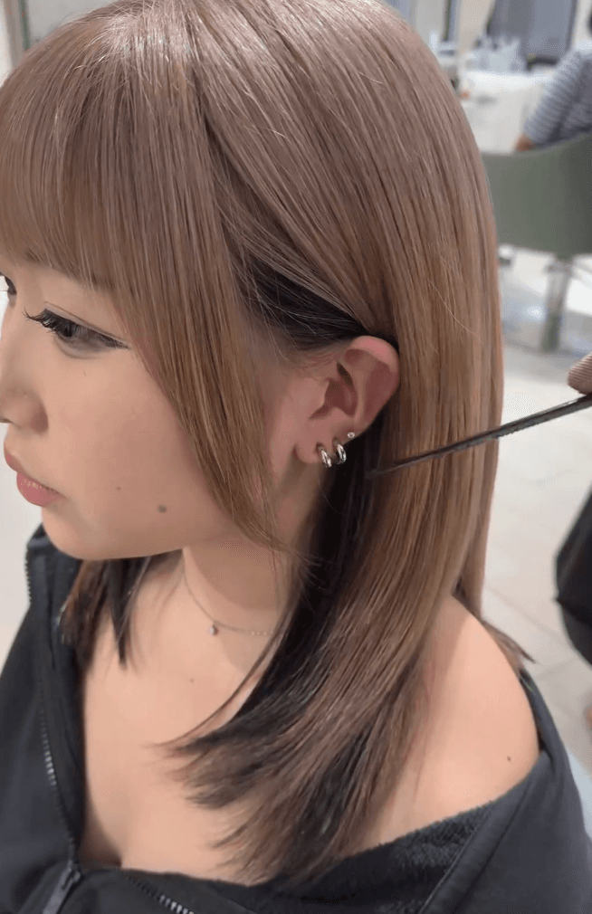 Sleek, straight ash brown hair with blunt bangs and a subtle black underlayer.