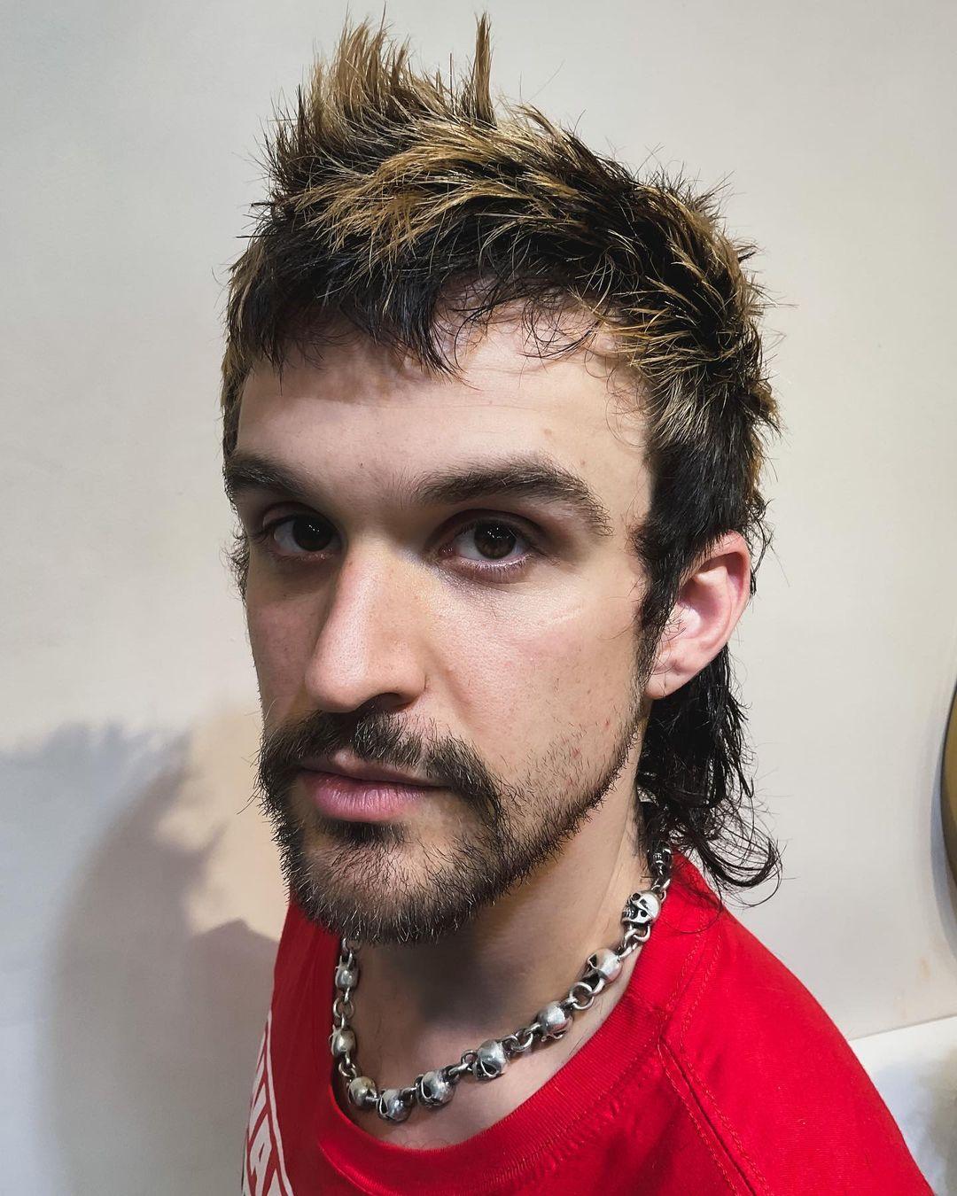A daring spiky top with dark brown base and blonde highlights, merging into a feathered mullet with choppy layers and a textured, wavy finish. 3
