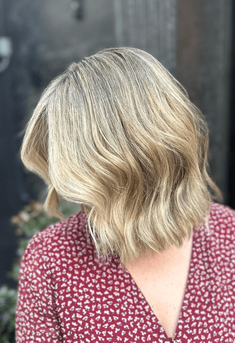Medium-length honey blonde wavy haircut with textured ends and balayage highlights.