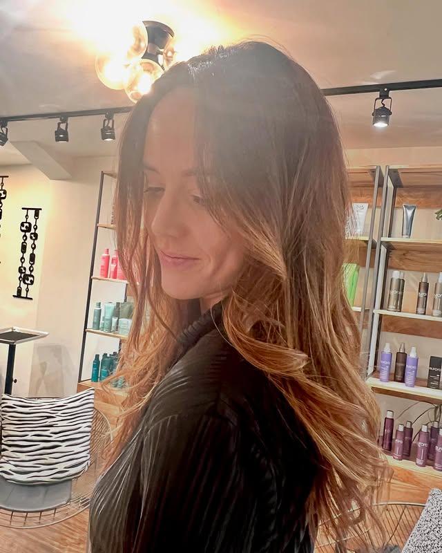 Long, wavy hair with a seamless balayage blending brown roots into caramel blonde highlights