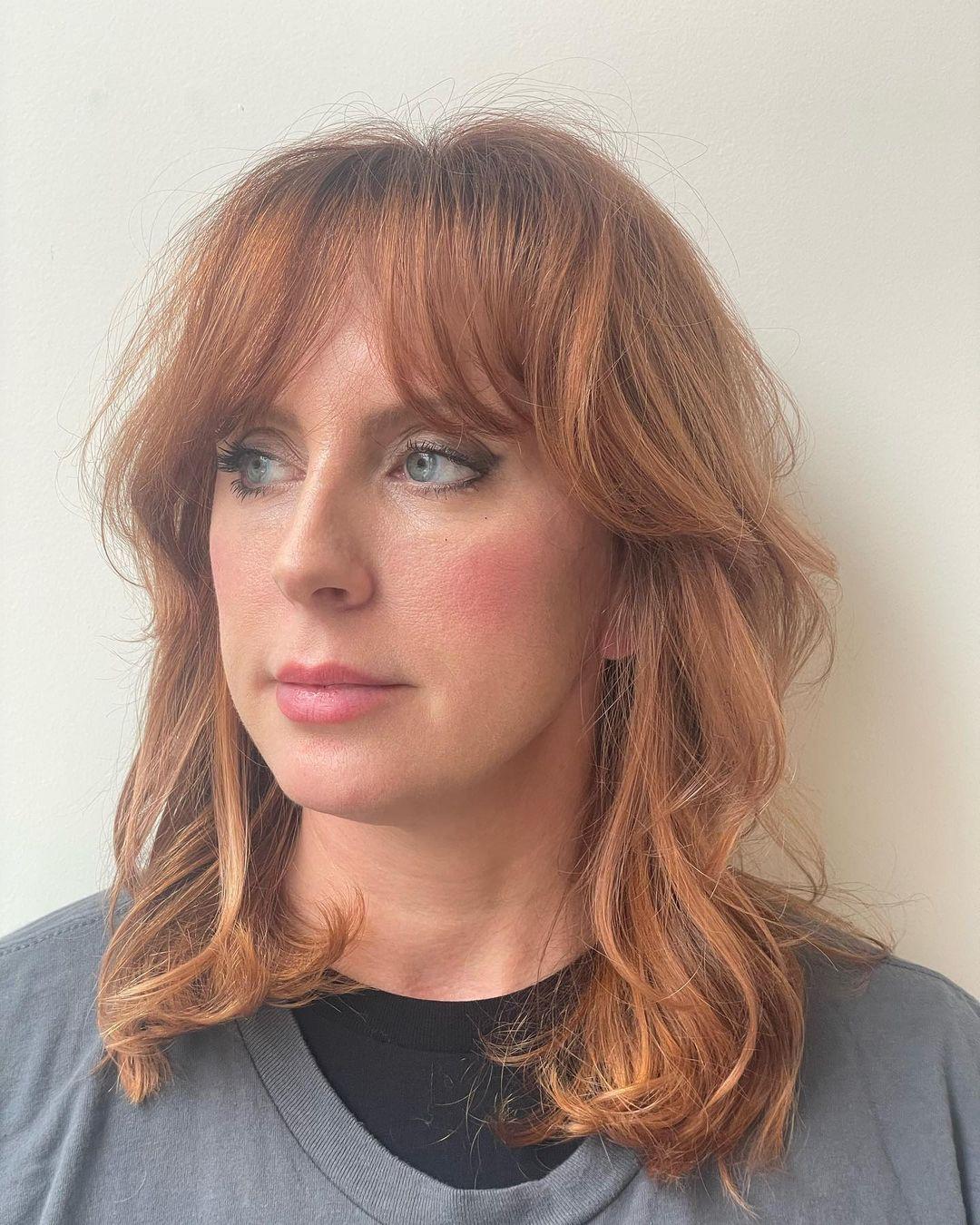 Medium-length, wavy hairstyle in a copper shade, featuring soft waves, long bangs, and a layered, face-framing cut. 1