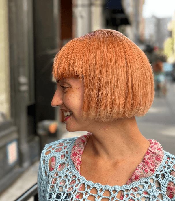 A short, straight, light orange bob with a blunt cut, straight fringe, glossy finish, and soft layers.


 1