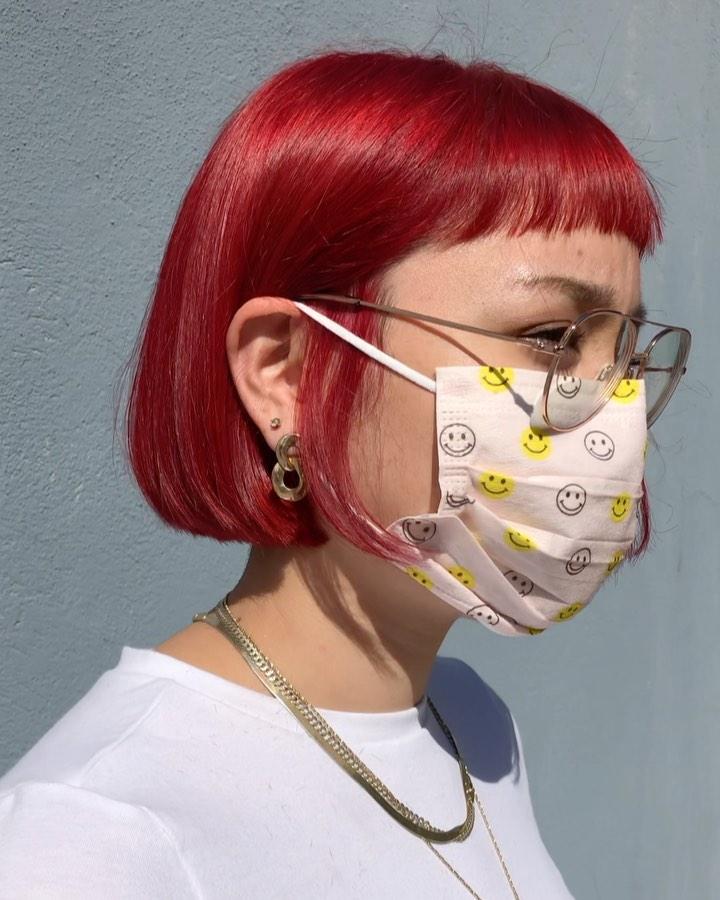 A vivid red, straight bob with blunt bangs at ear-length, featuring a sleek and glossy finish. 1