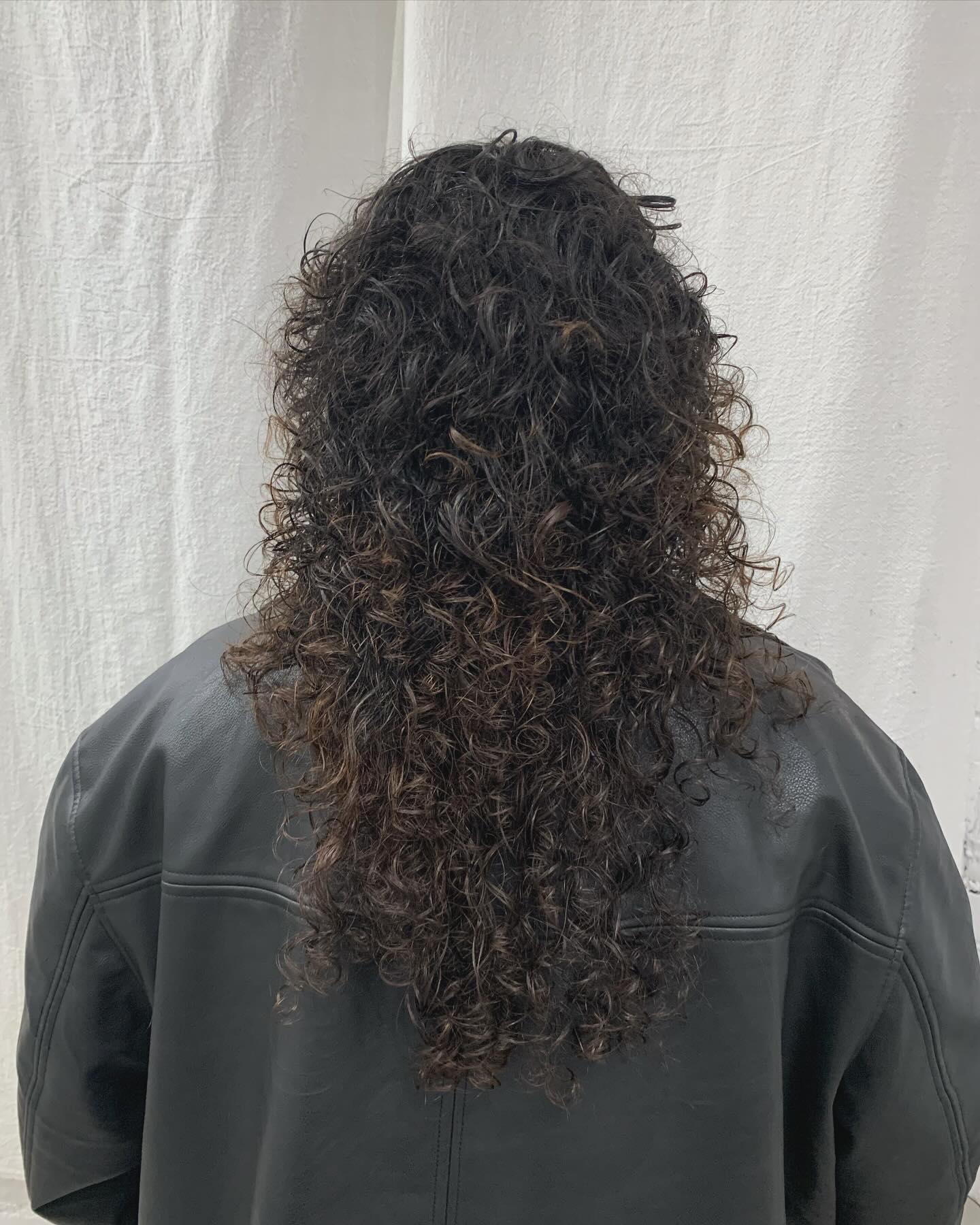 Long, dark brown curly hair with a full fringe and cascading voluminous ringlets. 4
