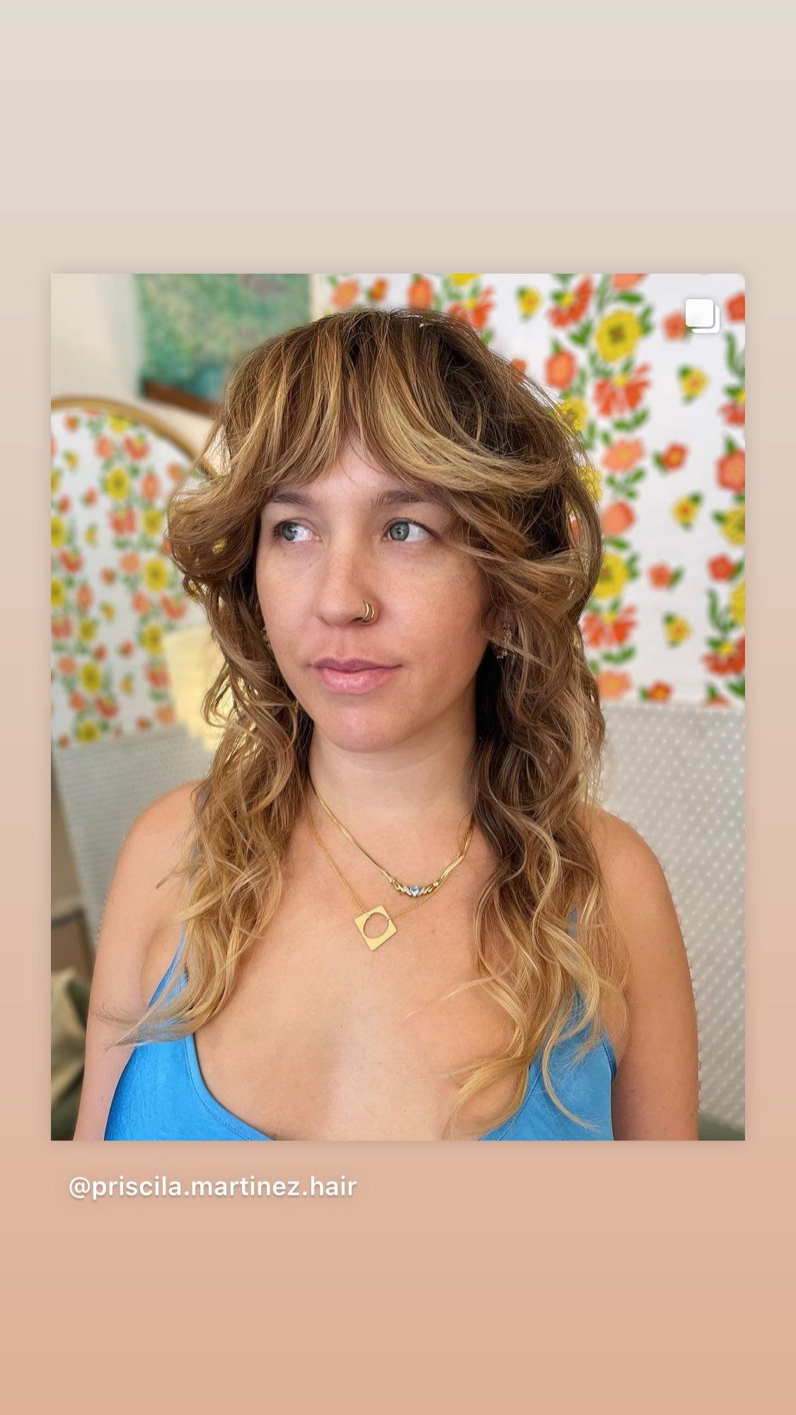 Retro shag with curtain bangs and sun-kissed highlights on wavy hair from Queen Of Swords