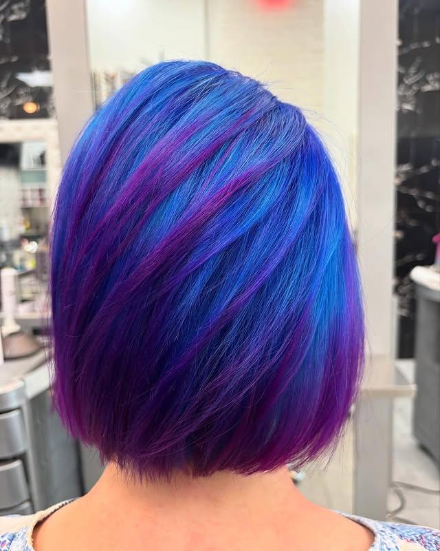 A sleek, straight bob with electric blue and purple highlights, showcasing vibrant and edgy hair color.