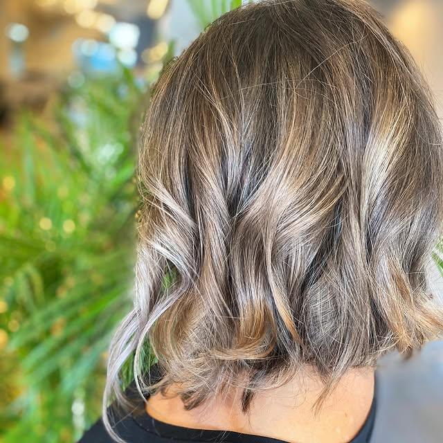 A layered bob with a soft, wavy texture and a blended bronde color. by Salon Phoenix