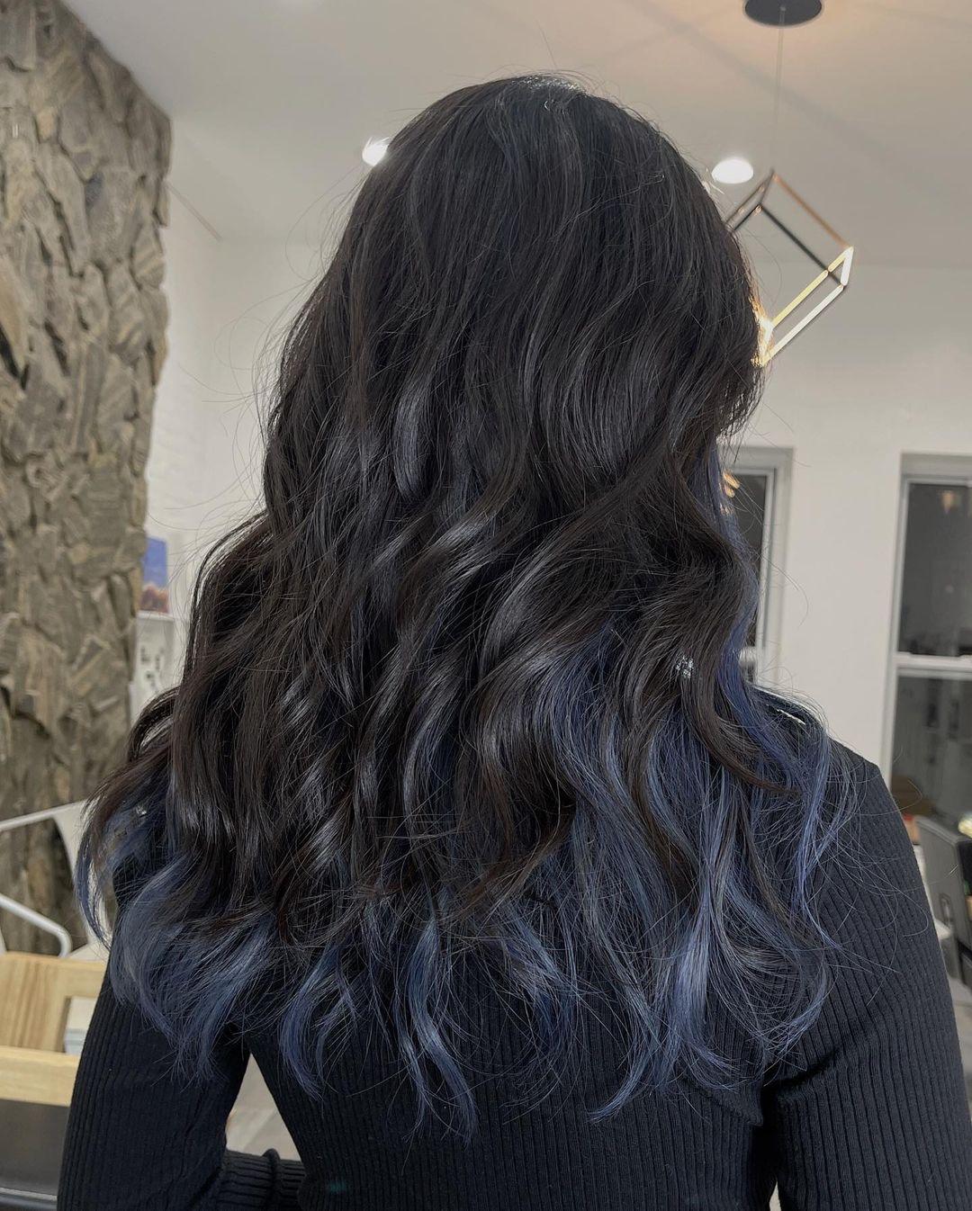 Medium-length, wavy hair with black to blue balayage, face-framing layers, and a stylish, voluminous texture. 3
