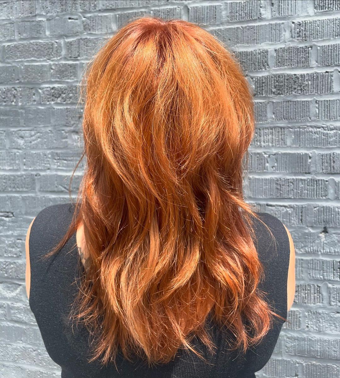 Medium-length cut with soft waves and a textured fringe, featuring a vibrant copper color. 2