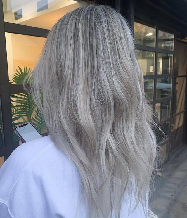 Icy blonde balayage on long, straight hair with platinum and silver hues