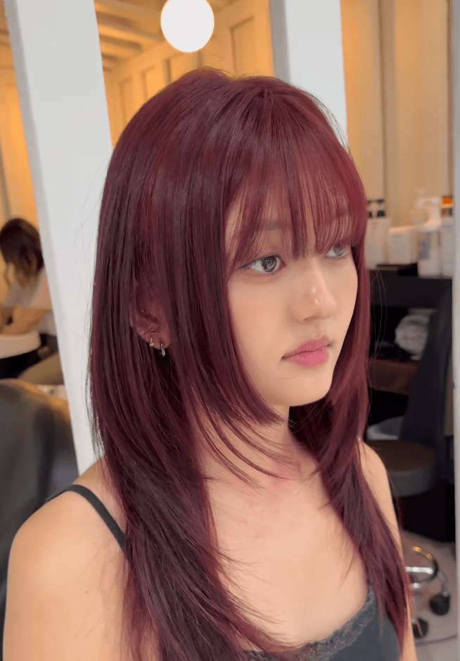 Long, straight hair in burgundy and maroon, with side-swept layers, a full fringe, and a glossy finish. 1