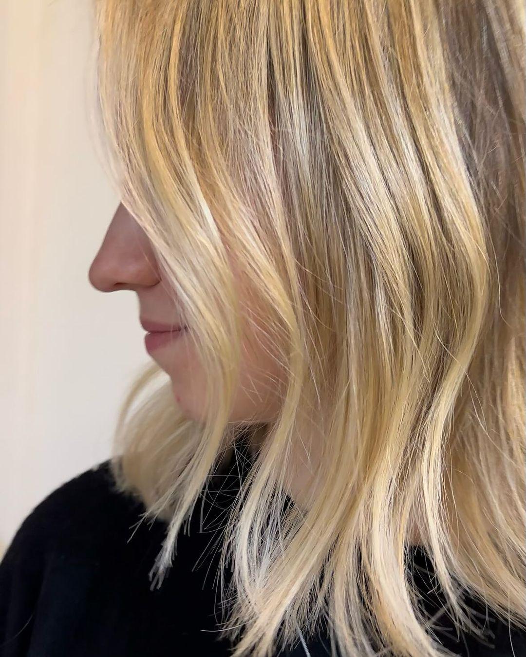 Medium-length wavy hair with sunlit balayage highlights and face-framing layers, creating a soft and radiant look. 2