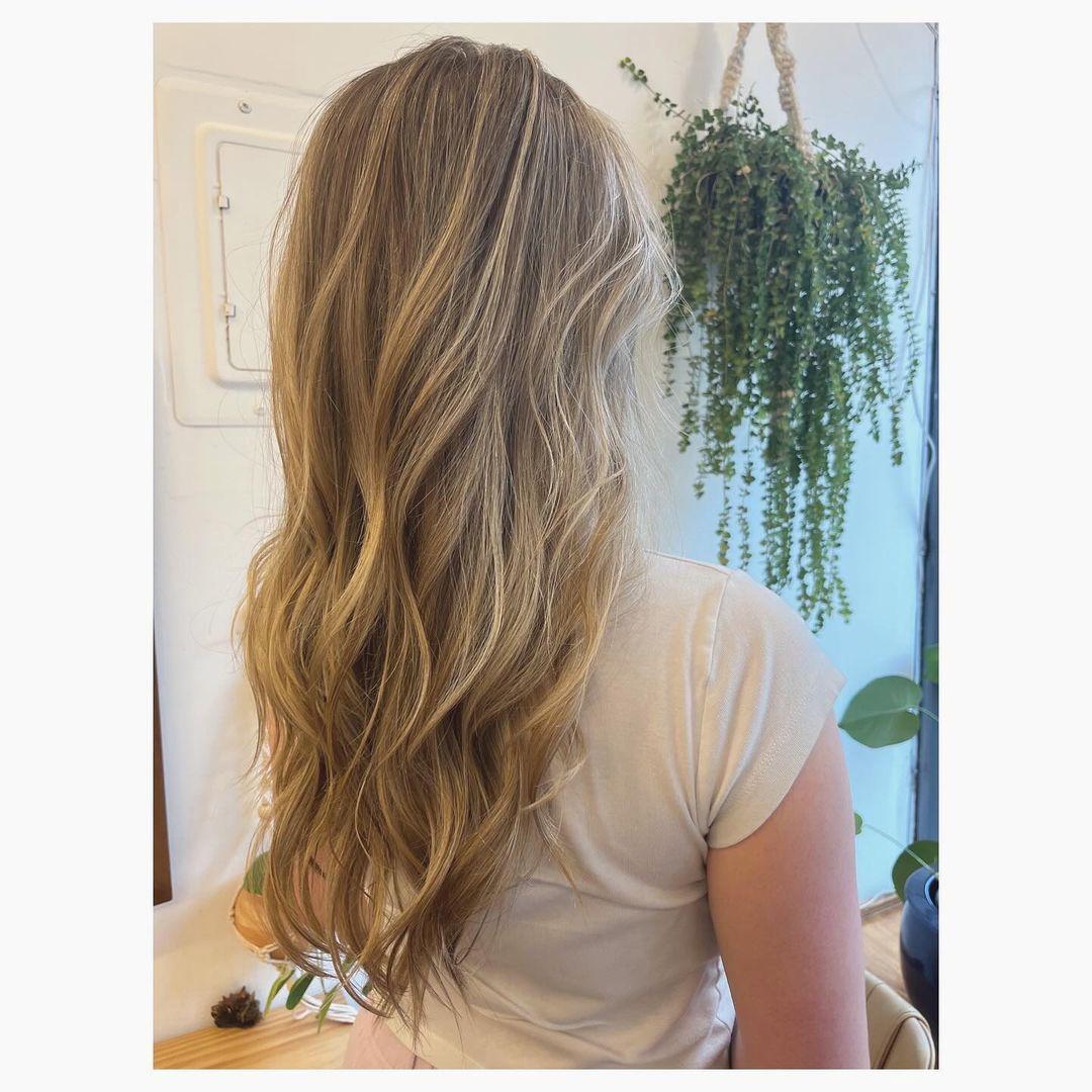 Long layered waves with honey blonde and golden highlights, a classic balayage style