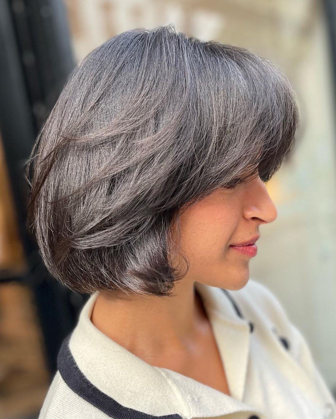 A stylish and modern short bob with a sophisticated blend of silver and grey. The straight hair features a side-swept fringe and layered sections for added movement and depth. 1